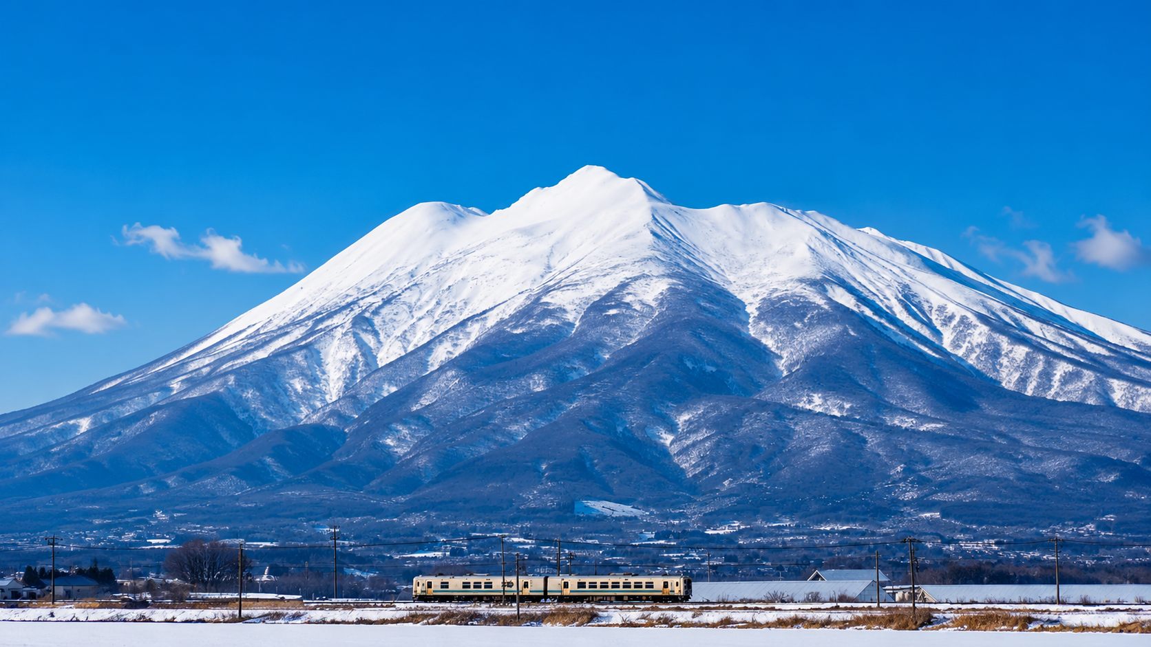 冬の岩木山とローカル線